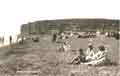 Tom Swaffield's boat amongst people enjoying themselves on the beach - and all dressed up too! c1920's